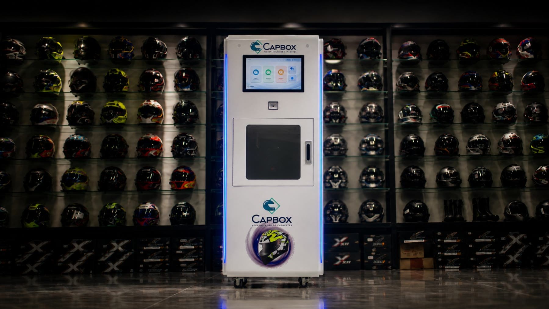 CapBox Pro em showroom, diante de uma parede de capacetes